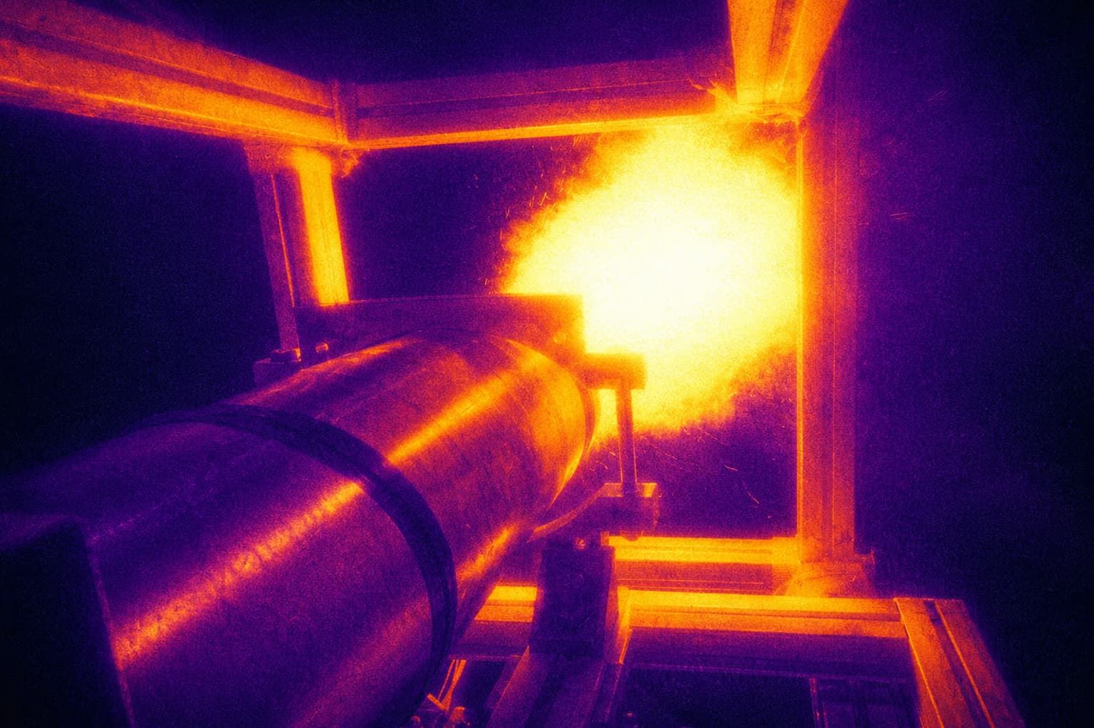 Imagen térmica del ensayo de un motor cohete de propulsión sólida: el cuerpo del motor y la llamarada en tonos naranja sobre fondo oscuro.